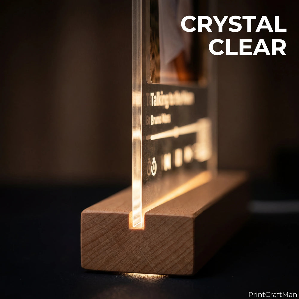Close-up of the 5mm clear cast acrylic edge glowing on the wooden LED base showing the engraved track title and player controls